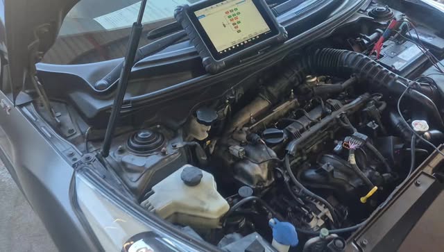 A diagnostic tablet resting on an open engine bay, mid scan.
