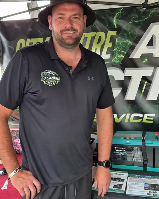 A City Centre Auto Electrical team member in a branded polo in front of the workshop backdrop.